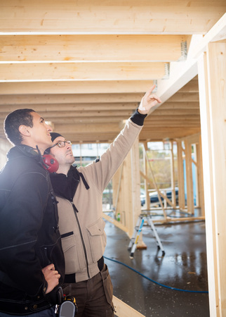 Carpenter Showing Wooden Roof To Colleague At Site