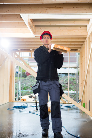 Carpenter Carrying Plank At Construction Site