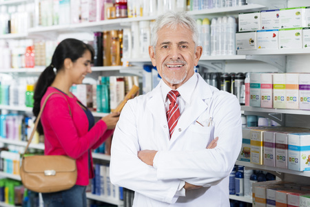 Smiling Chemist Standing Arms Crossed While Customer Choosing Prの写真素材