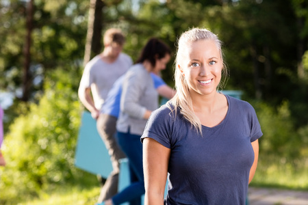Woman Smiling While Friends Making Pyramid Of Planks In Forest