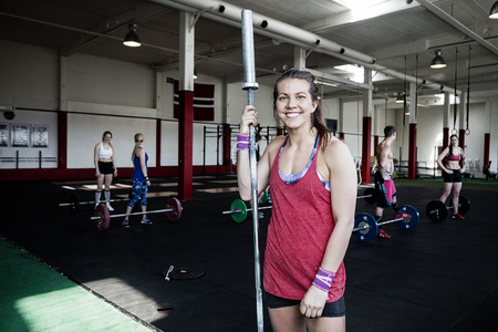 Happy Woman Holding Barbell Pole In Gymの写真素材