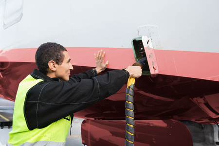 Male Crew Member Charging Airplane On Runway