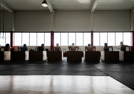 Rear View Of Men And Women Performing Triceps Dipsの写真素材