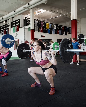 Woman Lifting Barbell With Friends In Gymの写真素材