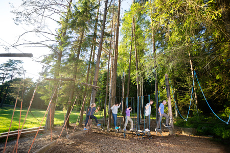 Multiethnic Coworkers Crossing Swinging Logs In Forestの写真素材