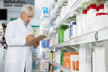 Pharmacist Holding Clipboard While Counting Stockの写真素材