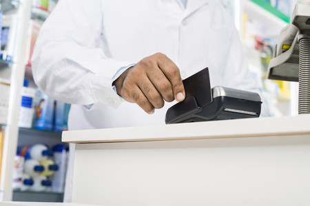 Midsection Of Pharmacist Swiping Credit Card On Readerの写真素材