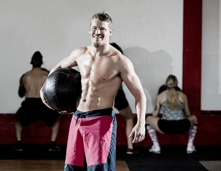 Muscular Man Holding Medicine Ball While Clients Exercisingの写真素材