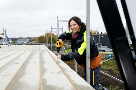 Female Carpenter Drilling Roof At Construction Siteの写真素材