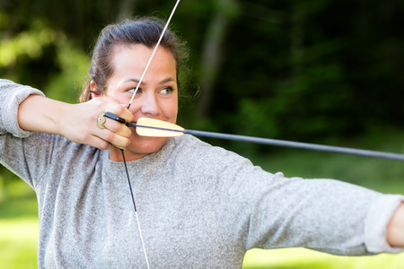 Confident Athlete Aiming With Bow And Arrow In Forestの写真素材