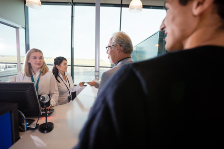 Staff And Passengers At Checking Counter In Airport