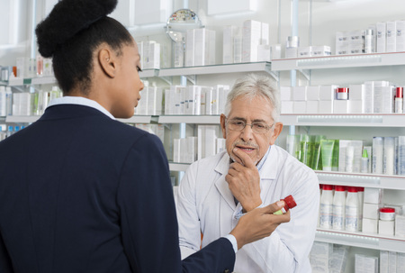 Pharmacist And Businesswoman Discussing Over Medicineの写真素材