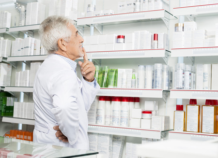 Thoughtful Senior Pharmacist Looking At Shelvesの写真素材