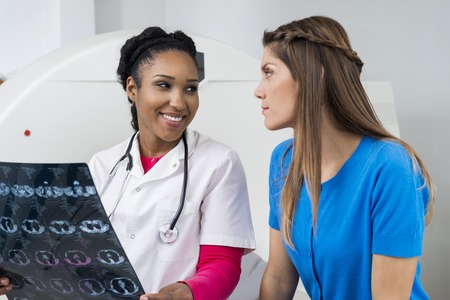 Female Doctor Holding Chest X-ray While Looking At Patientの写真素材