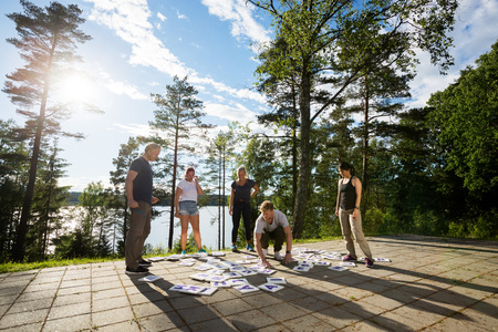 Full Length Of Friends Solving Crossword Puzzle On Patio In Foreの写真素材