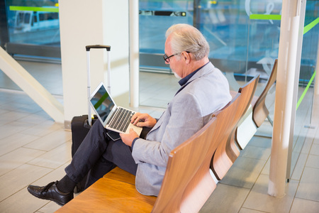 Businessman Using Laptop At Airport Terminalの写真素材
