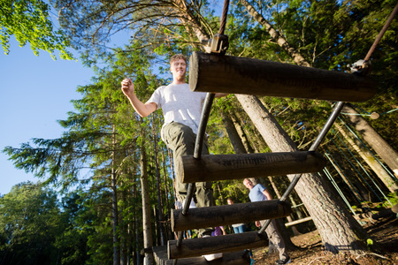 Young Businessman Crossing Log Bridge In Forestの写真素材