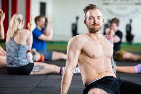 Confident Instructor Sitting While Clients Exercisingの写真素材