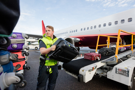 Worker Stacking Bags On Trailer At Runwayの写真素材