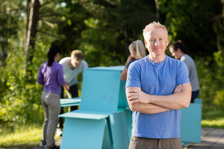 Man Standing Arms Crossed While Friends Making Planks Pyramidの写真素材