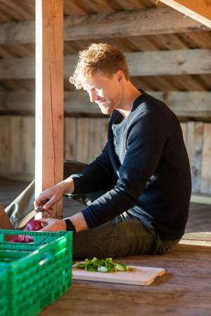 Man Cutting Onion While Sitting In Shedの写真素材