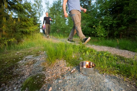 Businessmen Walking On Footpath By Lit Tealight Candle In Forestの写真素材