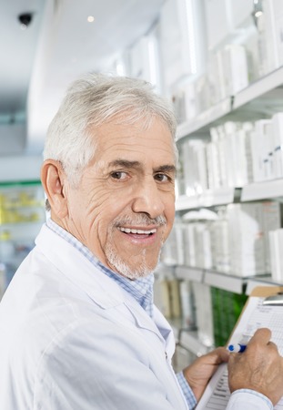 Smiling Senior Pharmacist Counting Stock In Drugstoreの写真素材