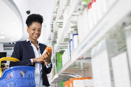 Businesswoman Holding Medicine By Shelves In Pharmacyの写真素材