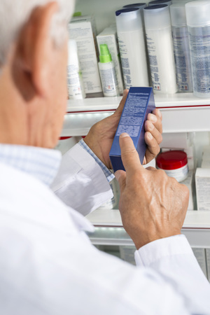 Pharmacist Reading Instructions On Medicine Box In Pharmacyの写真素材