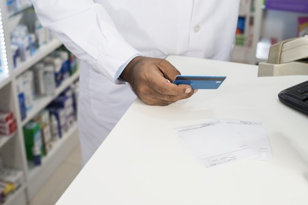 Chemist Holding Credit Card At Counter In Pharmacyの写真素材