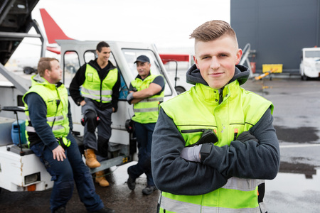 Worker With Arms Crossed Standing While Colleagues Communicatingの写真素材