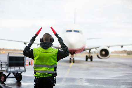 Ground Crew Signaling To Airplane On Wet Runwayの写真素材