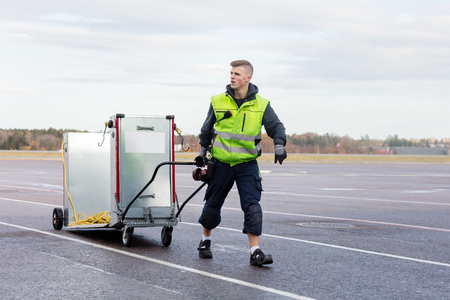 Worker Pulling Machine On Cart At Airport Runwayの写真素材