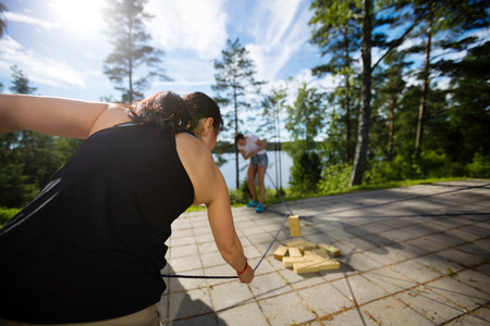 Woman Picking Up Wooden Block With Rope On Patioの写真素材