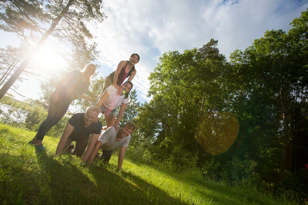 Tilt Image Of Happy Friends Making Human Pyramid In Forestの写真素材