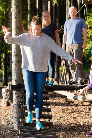 Confident Young Woman Crossing Log Bridge In Forestの写真素材