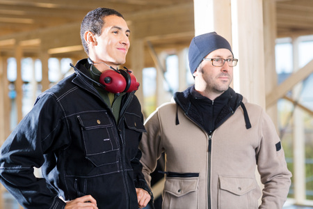 Carpenters In Jackets Looking Away While Standing At Siteの写真素材