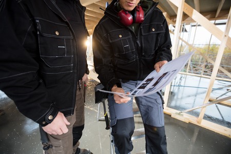Midsection Of Carpenters With Plan At Siteの写真素材