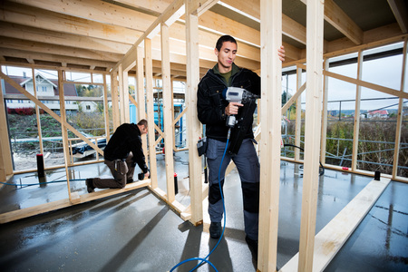 Carpenter Drilling Plank While Colleague Working At Constructionの写真素材