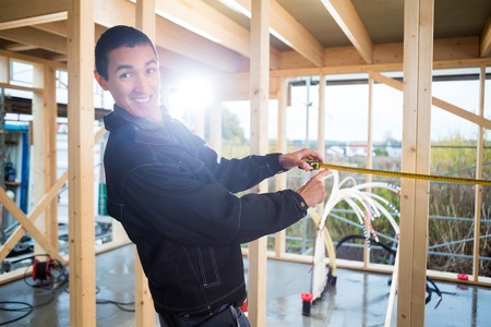 Carpenter Measuring Wood At Construction Siteの写真素材