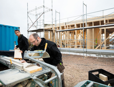 Carpenters Cutting Wood Using Table Saw At Site
