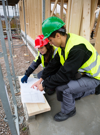 Carpenters Discussing Over Plan At Construction Siteの写真素材