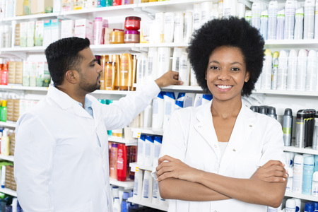 Pharmacist Standing Arms Crossed While Colleague Arranging Produの写真素材