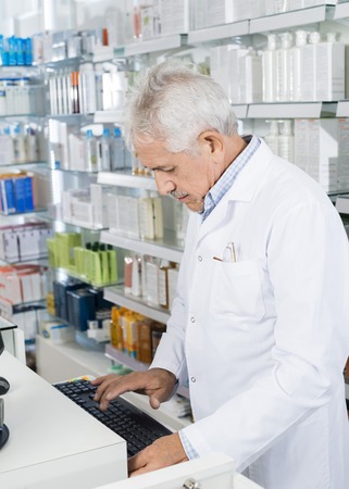 Pharmacist Using Computer Keyboard At Counterの写真素材