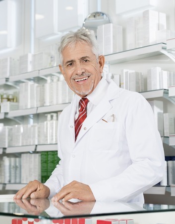 Confident Chemist Smiling At Counter In Pharmacyの写真素材