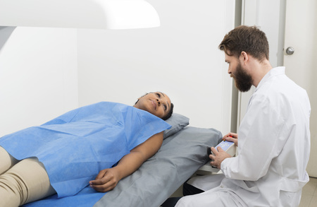 Woman Looking At Male Doctor Examining Her At Clinicの写真素材