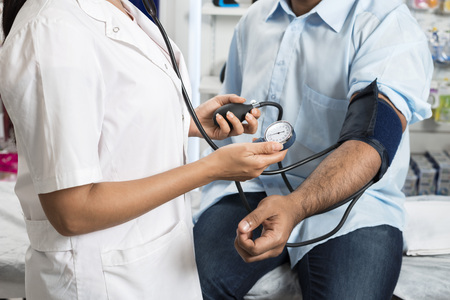 Doctor Holding Dial While Measuring Mans Blood Pressureの写真素材