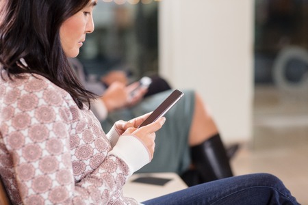Woman Using Mobile Phone While Waiting For Flight At Airportの写真素材