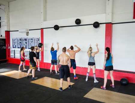 Men And Women Throwing Medicine Balls On Wall