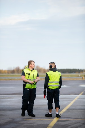 Workers In Reflective Jackets Standing On Airport Runwayの写真素材